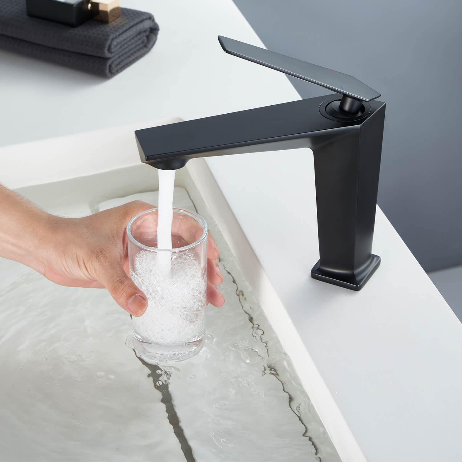 Filling a glass of water with a matte black splash proof bathroom faucet with aerator